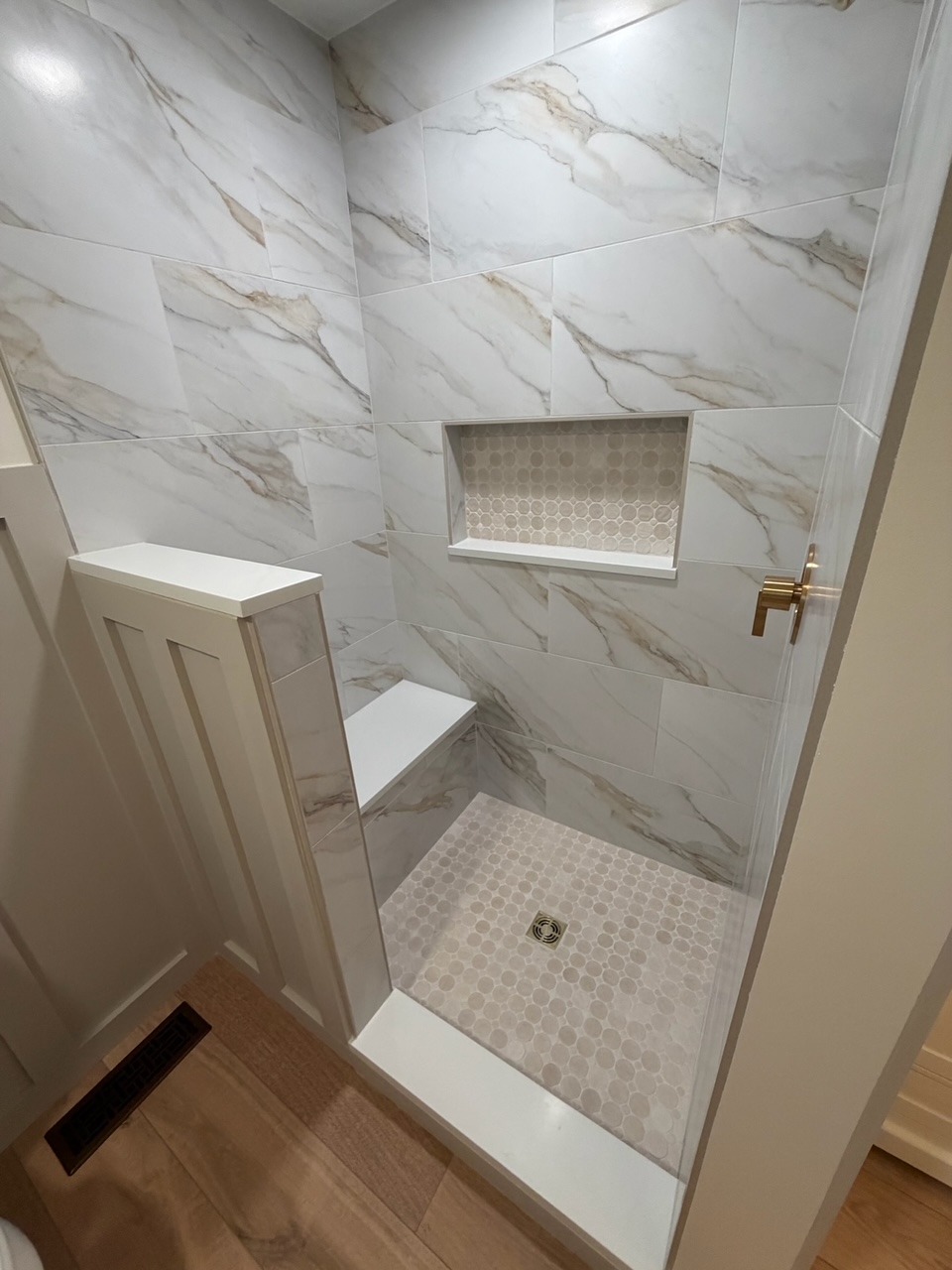 Close-up of shower bench, tile niche and mosaic shower floor