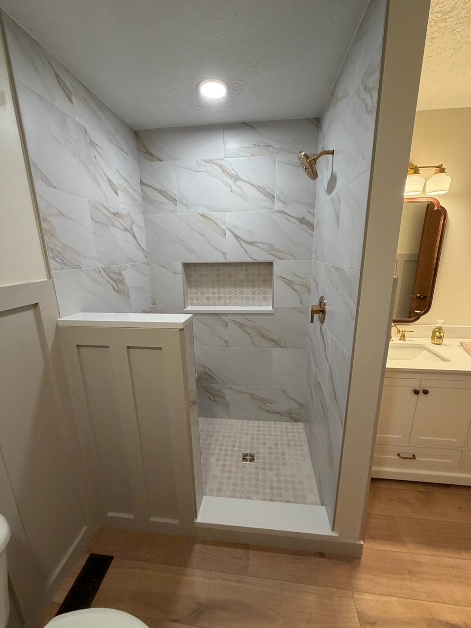 Custom marble-look tile walk-in shower with a recessed storage niche