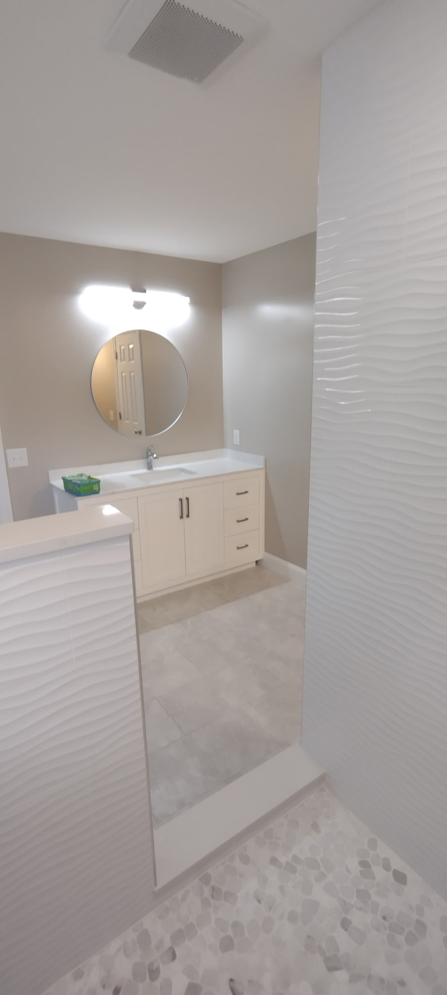 White vanity beside textured shower tile