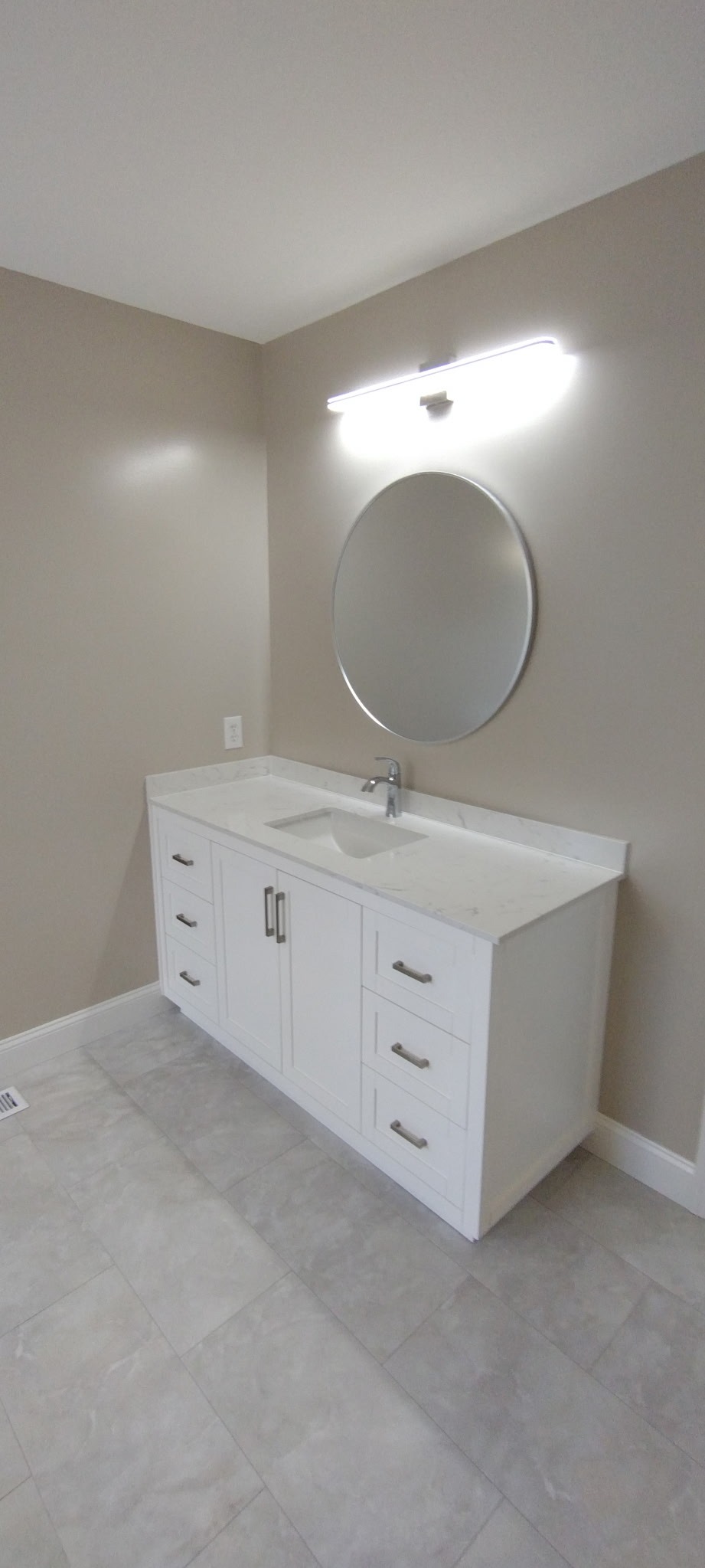 White bathroom vanity with round mirror and modern lighting