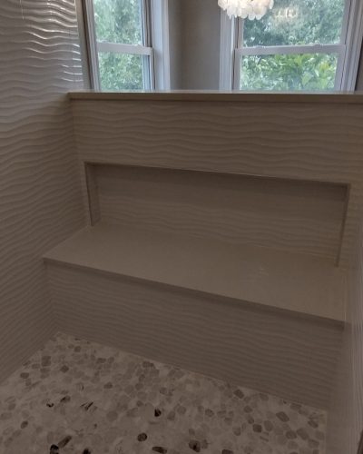 Strongsville shower bench with niche and pebble flooring